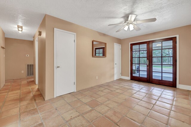 empty room featuring french doors, ceiling fan, and a textured ceiling