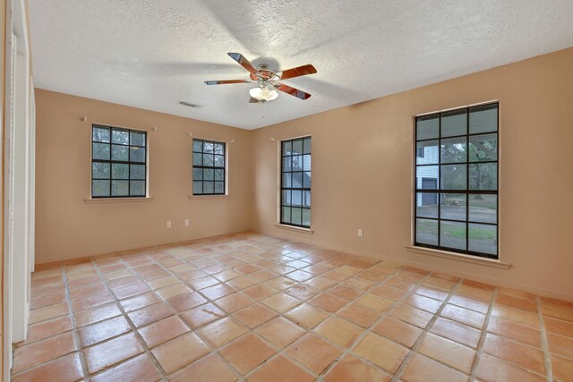 unfurnished room featuring ceiling fan, light tile patterned floors, and a textured ceiling