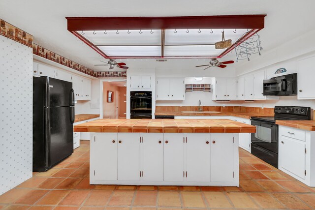 kitchen with ceiling fan, black appliances, a center island, and white cabinets