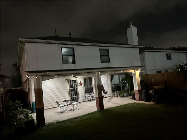 back house at twilight with a yard and a patio area