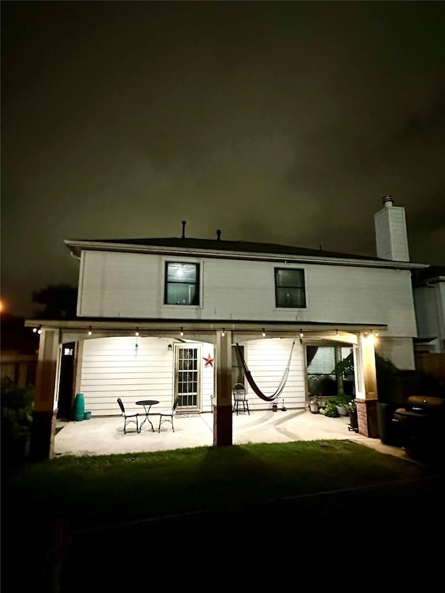 back house at twilight with a patio area