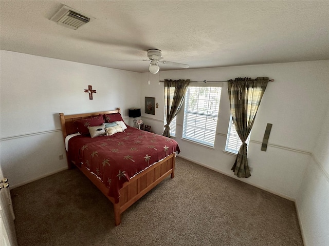 bedroom with a textured ceiling, carpet floors, and ceiling fan