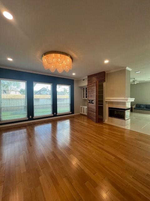 unfurnished living room with wood-type flooring and ornamental molding