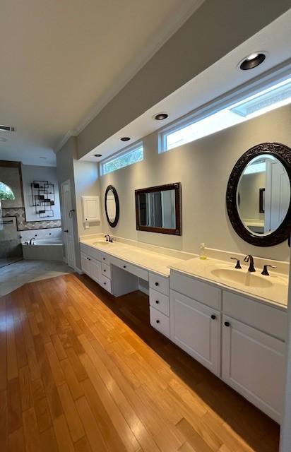 bathroom featuring crown molding, hardwood / wood-style floors, vanity, and a washtub