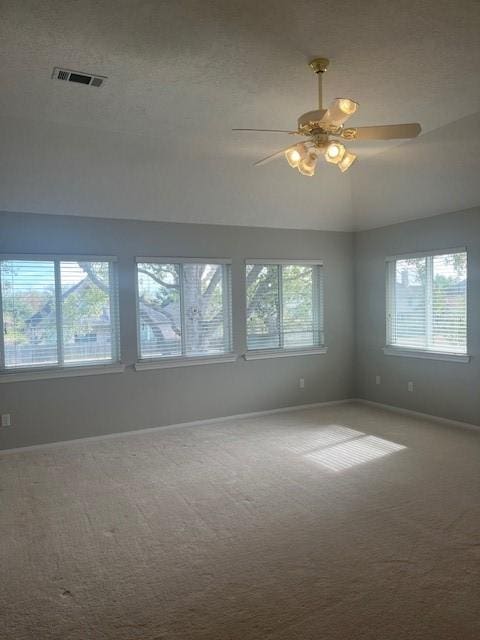 carpeted spare room featuring a textured ceiling, vaulted ceiling, and ceiling fan