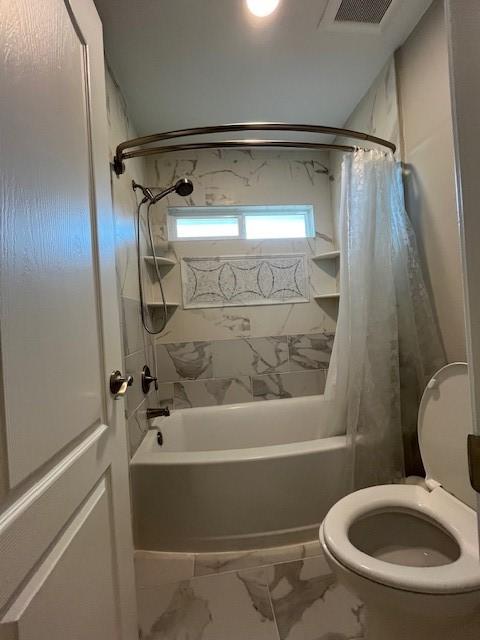 bathroom with toilet and shower / bath combo with shower curtain