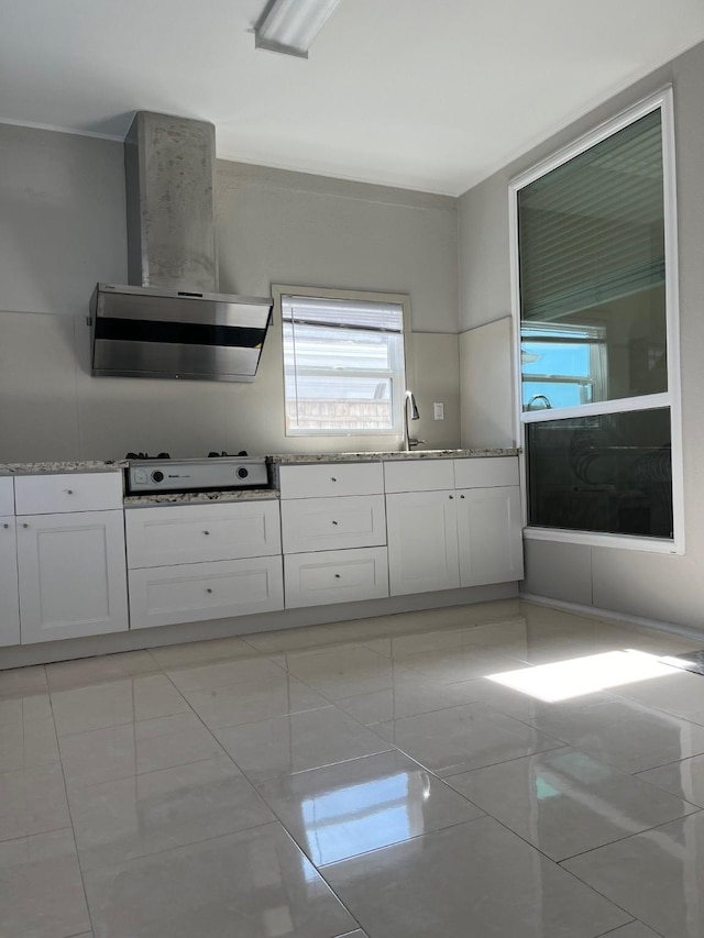 kitchen with ventilation hood, sink, light tile patterned floors, stovetop, and white cabinetry