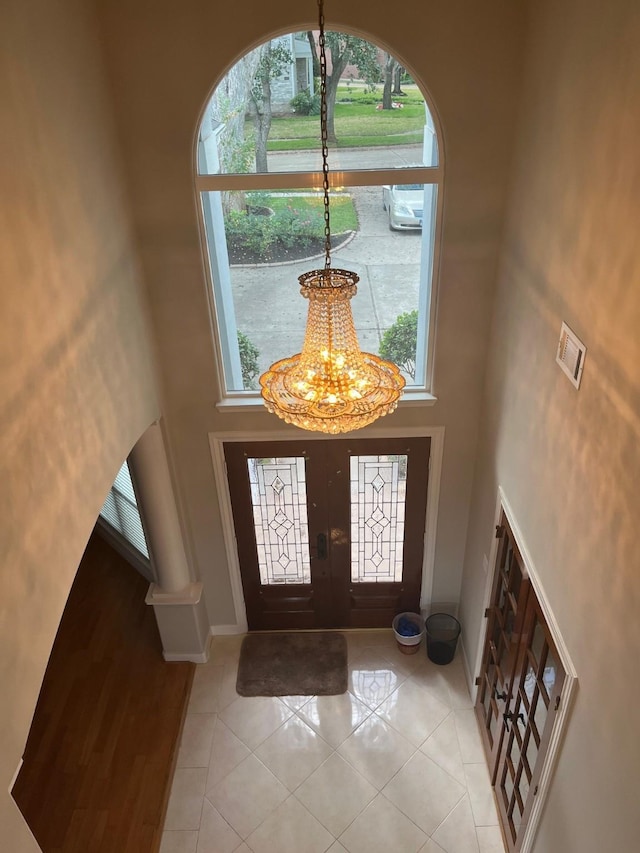 foyer entrance with french doors, light tile patterned floors, a healthy amount of sunlight, and a high ceiling