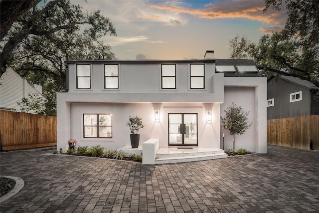 back house at dusk with french doors and a patio area