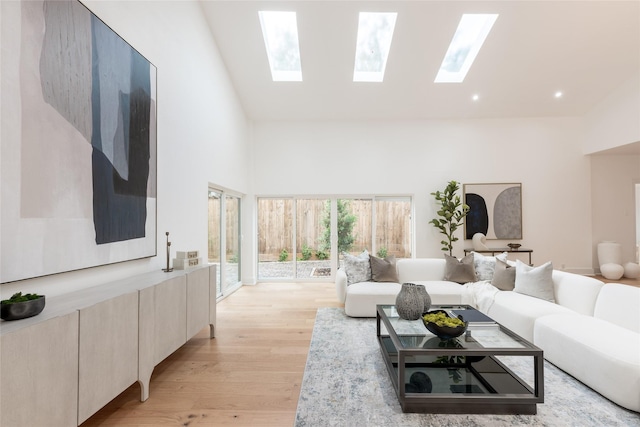 living room featuring a skylight, light hardwood / wood-style flooring, and high vaulted ceiling