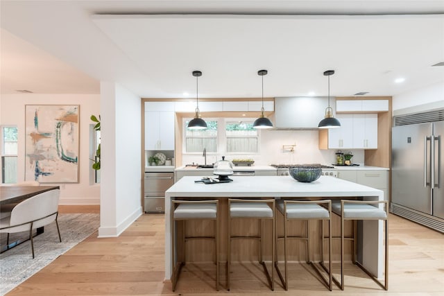 kitchen featuring white cabinets, a kitchen island, light wood-type flooring, and appliances with stainless steel finishes