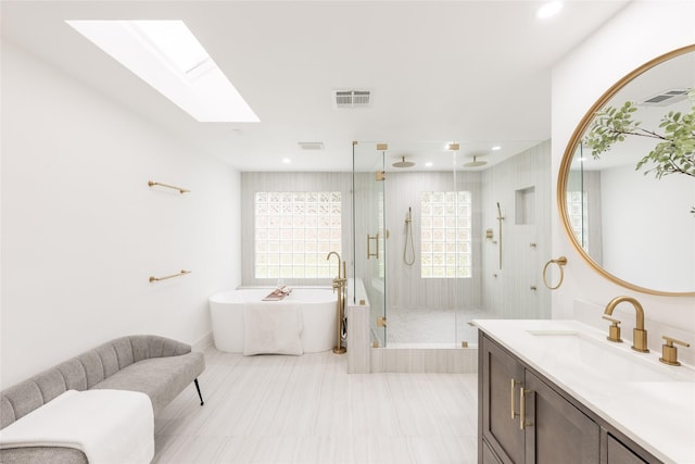 bathroom with vanity, shower with separate bathtub, and a skylight