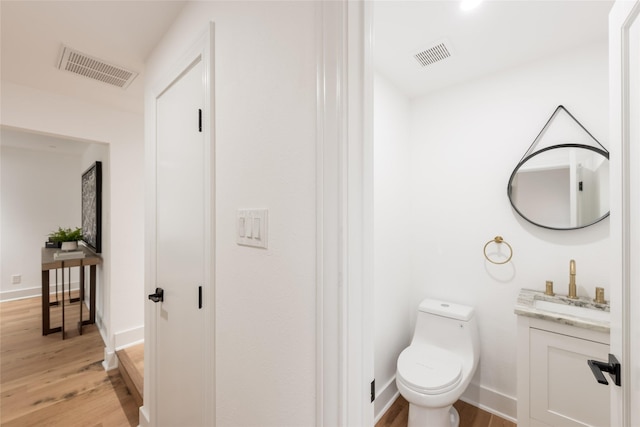 bathroom with hardwood / wood-style flooring, vanity, and toilet