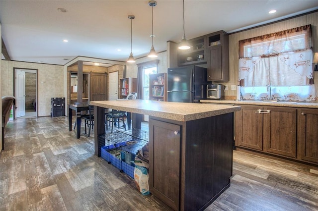 kitchen featuring a center island, sink, dark wood-type flooring, decorative light fixtures, and black refrigerator