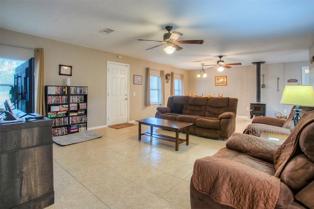 tiled living room with ceiling fan and a wood stove