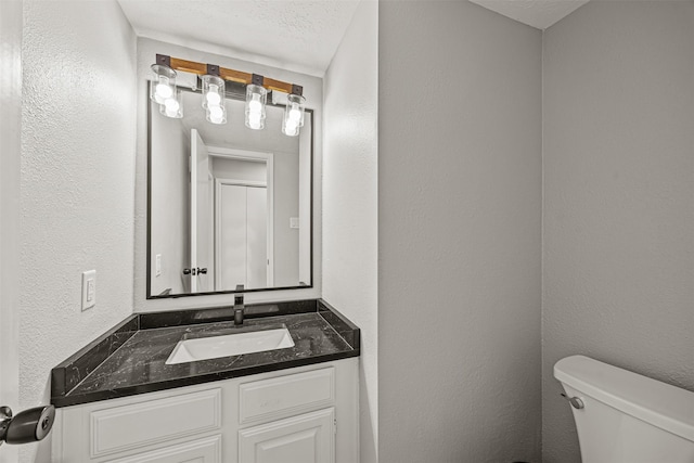 bathroom with vanity, a textured ceiling, and toilet