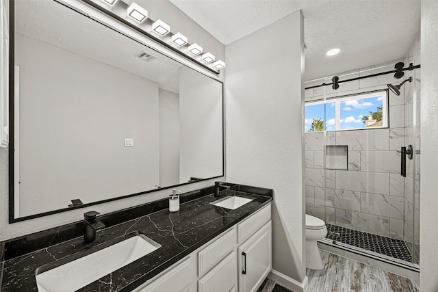 bathroom featuring vanity, a textured ceiling, wood-type flooring, toilet, and a shower with shower door