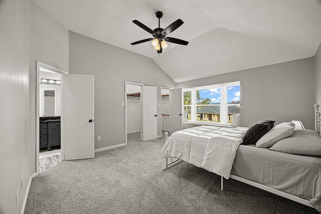 carpeted bedroom featuring connected bathroom, ceiling fan, lofted ceiling, a walk in closet, and a closet