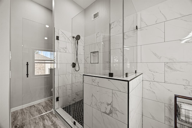 bathroom with a tile shower and hardwood / wood-style floors