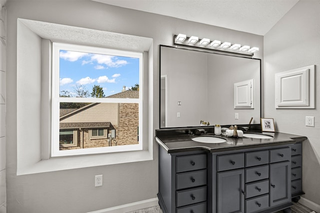 bathroom with a textured ceiling, vanity, and vaulted ceiling