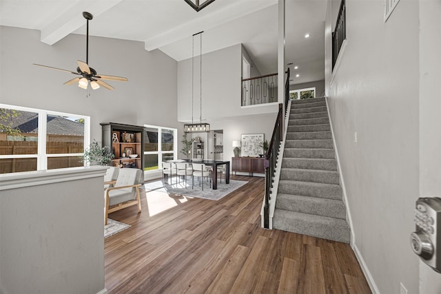 stairway with hardwood / wood-style floors, high vaulted ceiling, and a wealth of natural light