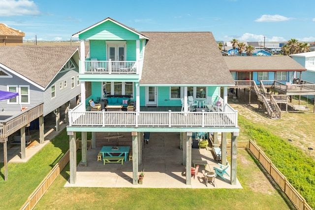 back of house featuring a lawn, an outdoor living space, a balcony, a wooden deck, and a patio area