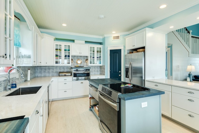 kitchen featuring ornamental molding, stainless steel appliances, sink, light hardwood / wood-style flooring, and white cabinets