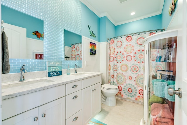 bathroom featuring vanity, crown molding, toilet, tile walls, and tasteful backsplash