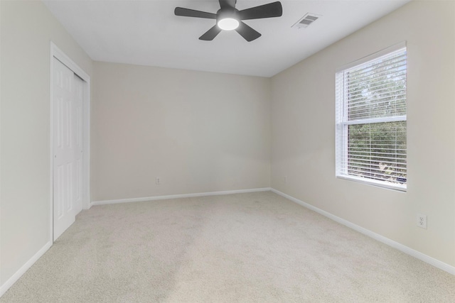 unfurnished room with ceiling fan, light carpet, and a wealth of natural light