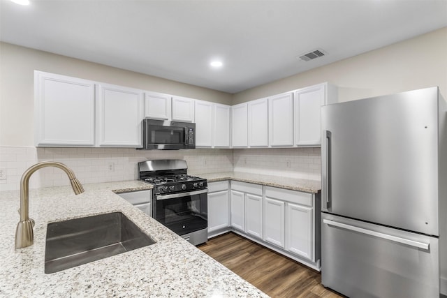 kitchen with light stone countertops, appliances with stainless steel finishes, white cabinetry, and sink