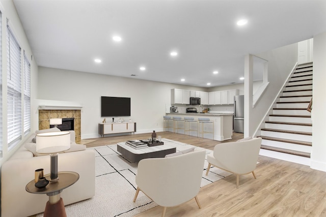 living room with a tile fireplace and light wood-type flooring