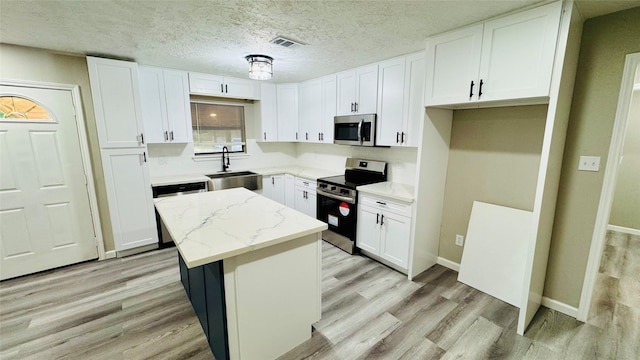 kitchen with white cabinets, a kitchen island, sink, and stainless steel appliances