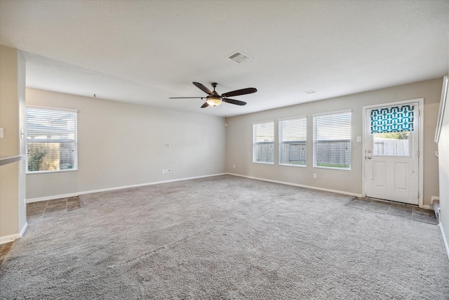 carpeted spare room featuring ceiling fan and a healthy amount of sunlight