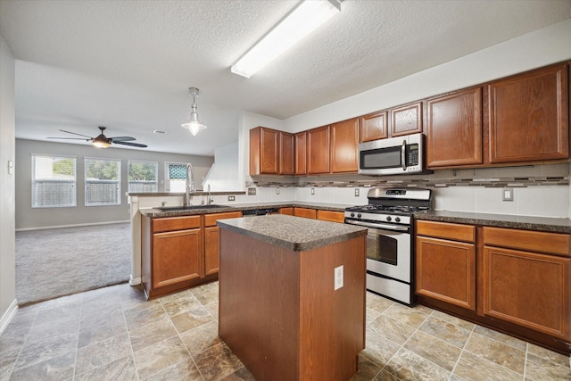 kitchen featuring kitchen peninsula, stainless steel appliances, ceiling fan, pendant lighting, and a kitchen island