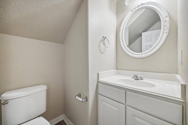 bathroom with vanity, a textured ceiling, toilet, and vaulted ceiling