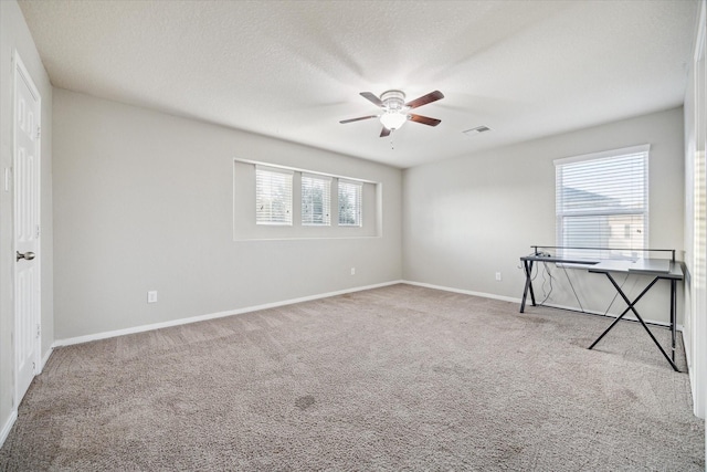 carpeted empty room featuring plenty of natural light, ceiling fan, and a textured ceiling