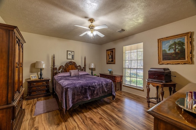 bedroom featuring a textured ceiling, ceiling fan, and dark wood-type flooring