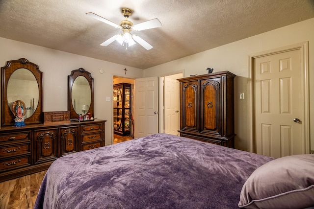 bedroom featuring hardwood / wood-style floors, ceiling fan, and a textured ceiling