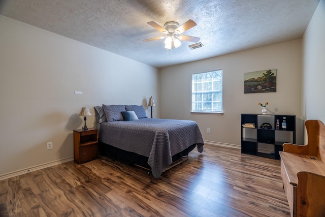 bedroom with ceiling fan, dark hardwood / wood-style flooring, and a textured ceiling