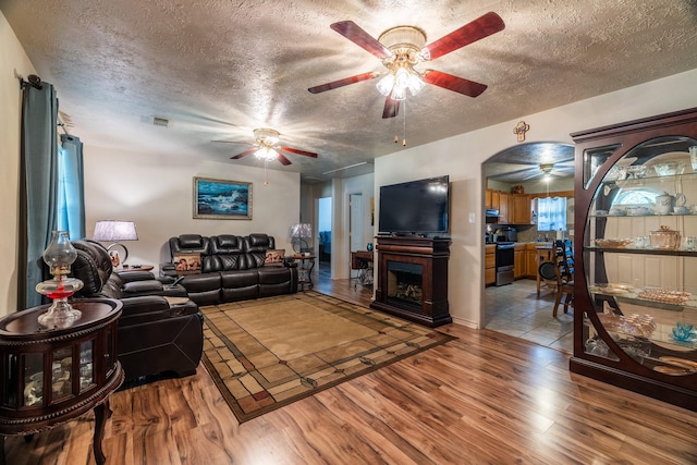 living room featuring a fireplace, a textured ceiling, and light hardwood / wood-style flooring