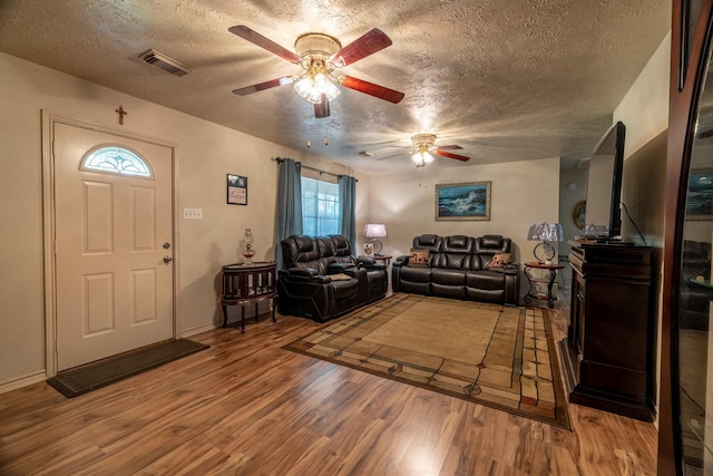 living room with hardwood / wood-style floors, a textured ceiling, and ceiling fan