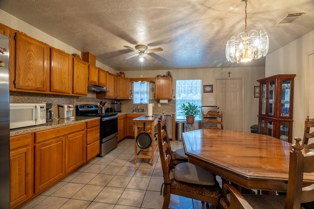 kitchen with stainless steel range with electric stovetop, ceiling fan with notable chandelier, a textured ceiling, pendant lighting, and light tile patterned floors