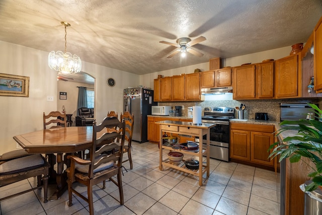 kitchen featuring stainless steel appliances, pendant lighting, a textured ceiling, decorative backsplash, and ceiling fan with notable chandelier