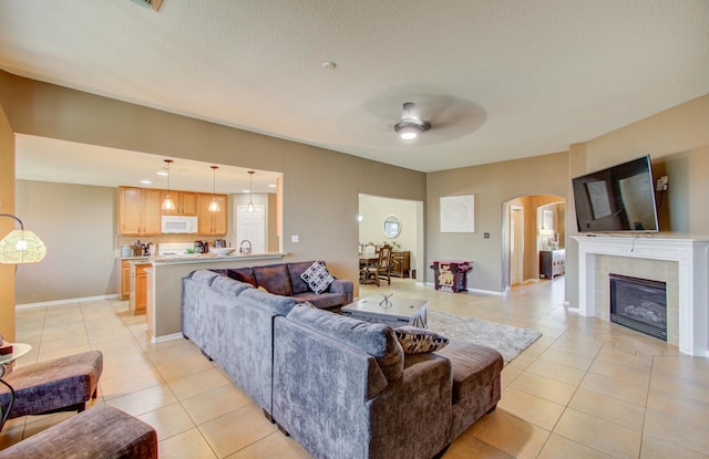 tiled living room featuring a textured ceiling, ceiling fan, and a tiled fireplace