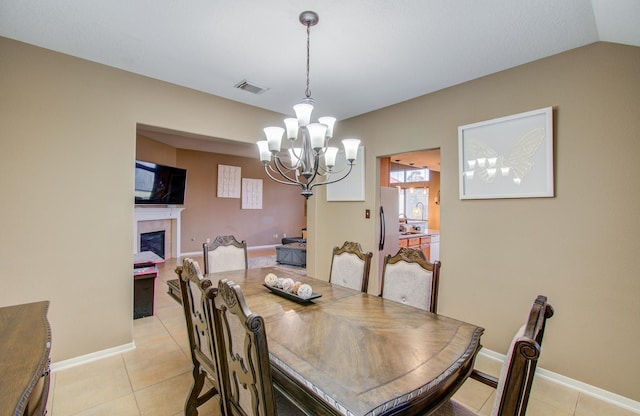 dining room featuring a fireplace, a chandelier, vaulted ceiling, and light tile patterned flooring