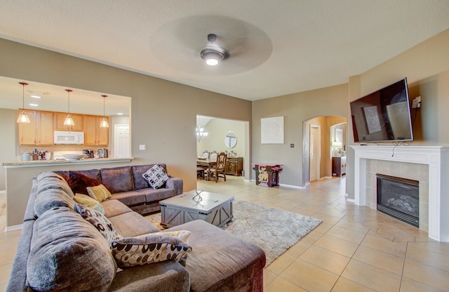 tiled living room featuring a tile fireplace, a textured ceiling, and ceiling fan