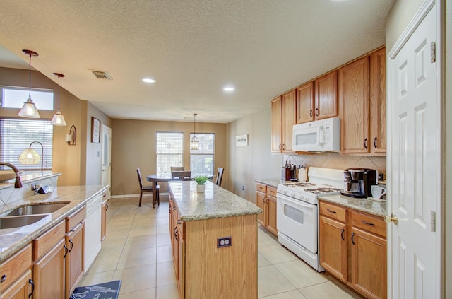 kitchen with sink, light stone counters, decorative light fixtures, white appliances, and a kitchen island