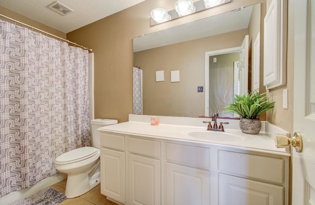 bathroom with tile patterned flooring, vanity, a textured ceiling, and toilet