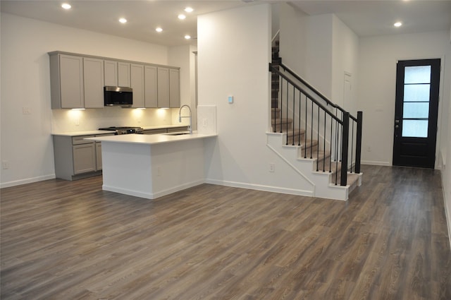 kitchen featuring kitchen peninsula, appliances with stainless steel finishes, sink, gray cabinets, and dark hardwood / wood-style floors