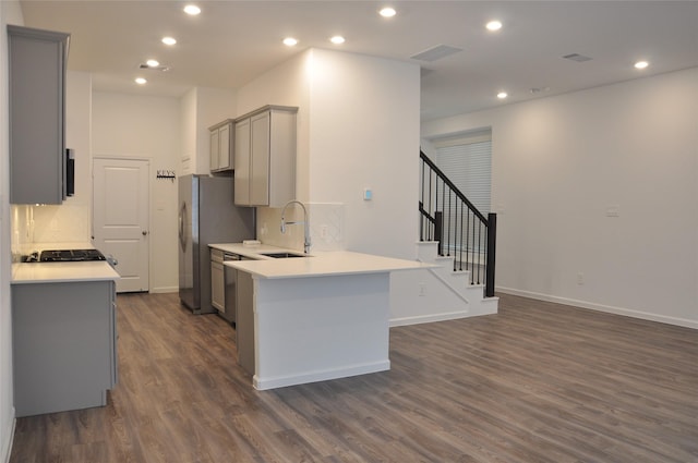 kitchen with decorative backsplash, kitchen peninsula, gray cabinetry, dark wood-type flooring, and sink